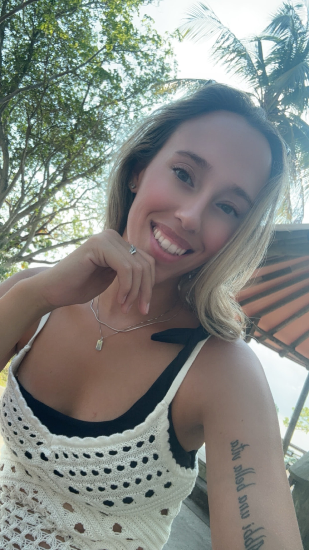 Anne King smiling outdoors beneath palm trees.